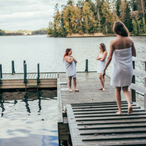 Kolme naista seisoo laiturilla pyyhkeet yllään.