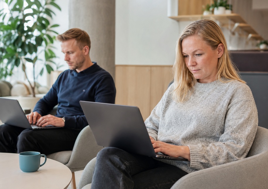 Nainen ja mies istuvat nojatuoleissa, kannettavat tietokoneet syleissään.