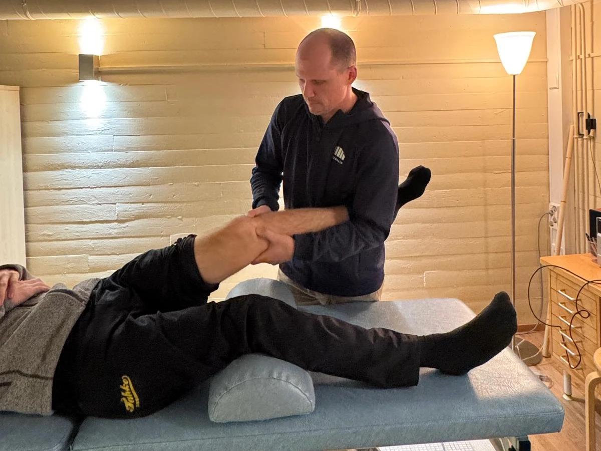 Fysioterapeutti käsittelee urheilijan polvea hierontapöydällä Kisakallion urheiluopistolla