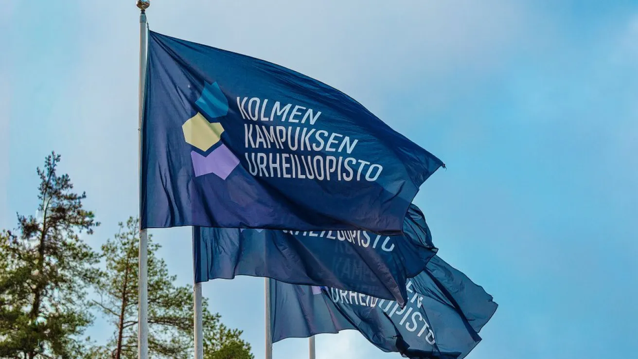 Kolmen kampuksen urheiluopiston tummansiniset liput liehumassa lipputangoissa